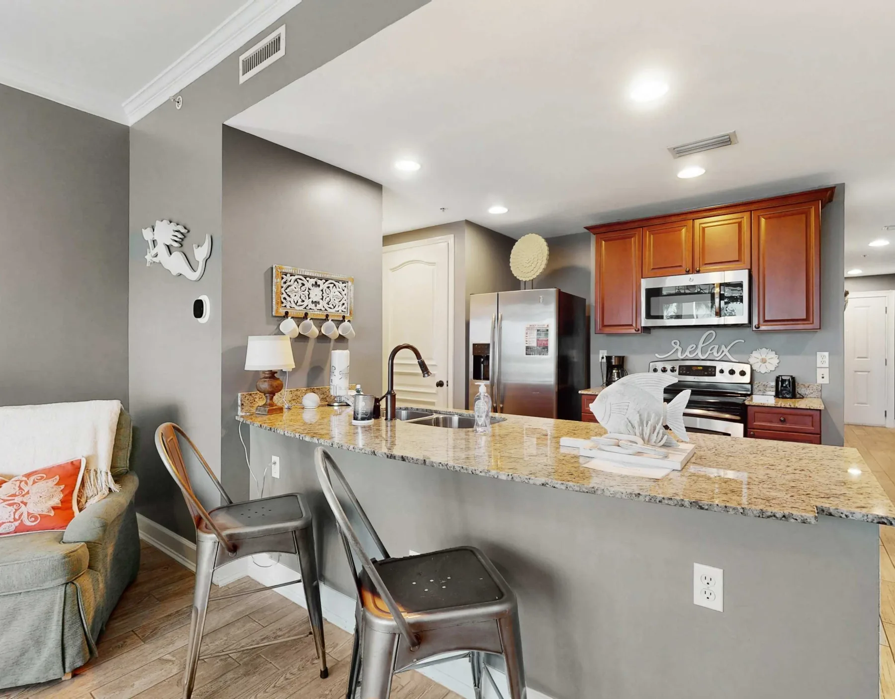 An open kitchen with a granite island, bar seating, and a living area nearby.