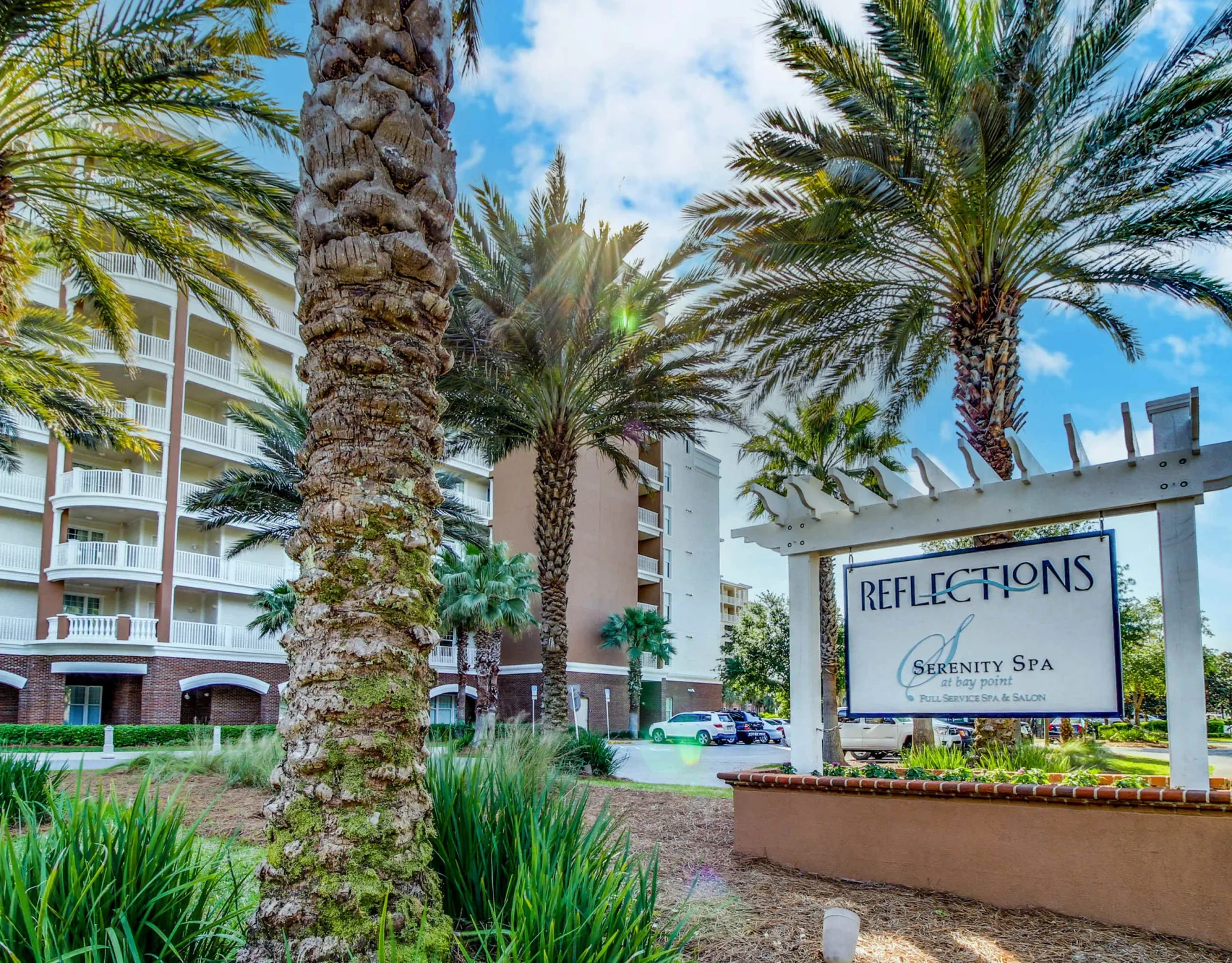 Shared amenity: Palm trees and landscaped greenery surround a sign in front of a multi-story building.
