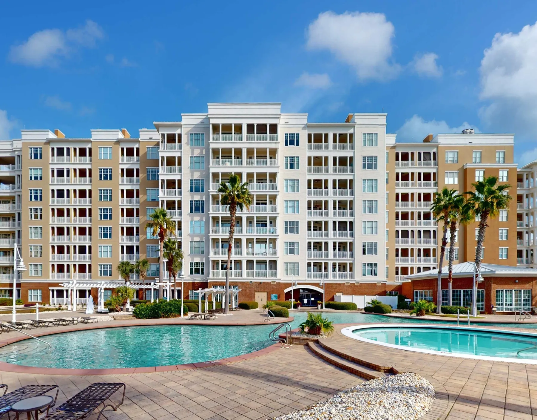 Shared amenity: Apartment building overlooking an outdoor pool and paved deck.