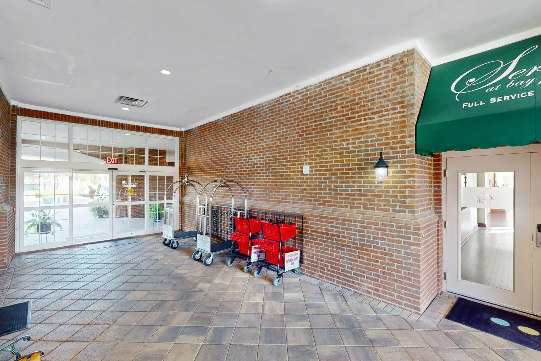Shared amenity: A tiled entrance area with brick walls, luggage carts, and a green awning.