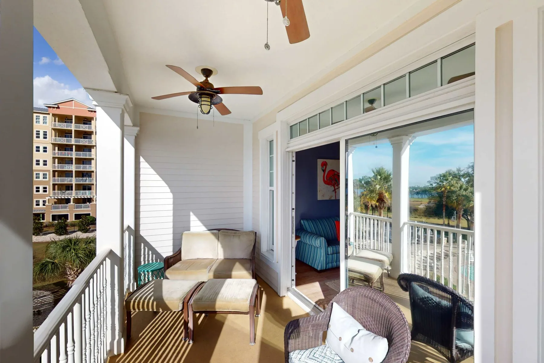 A bright enclosed porch with seating and large windows overlooking greenery.