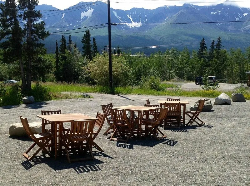 Representative hotel space: Outdoor dining tables and seating overlook a forested landscape and mountain range.