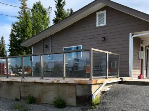Representative hotel space: A modern building with a glass-railed outdoor deck and gravel beside it.