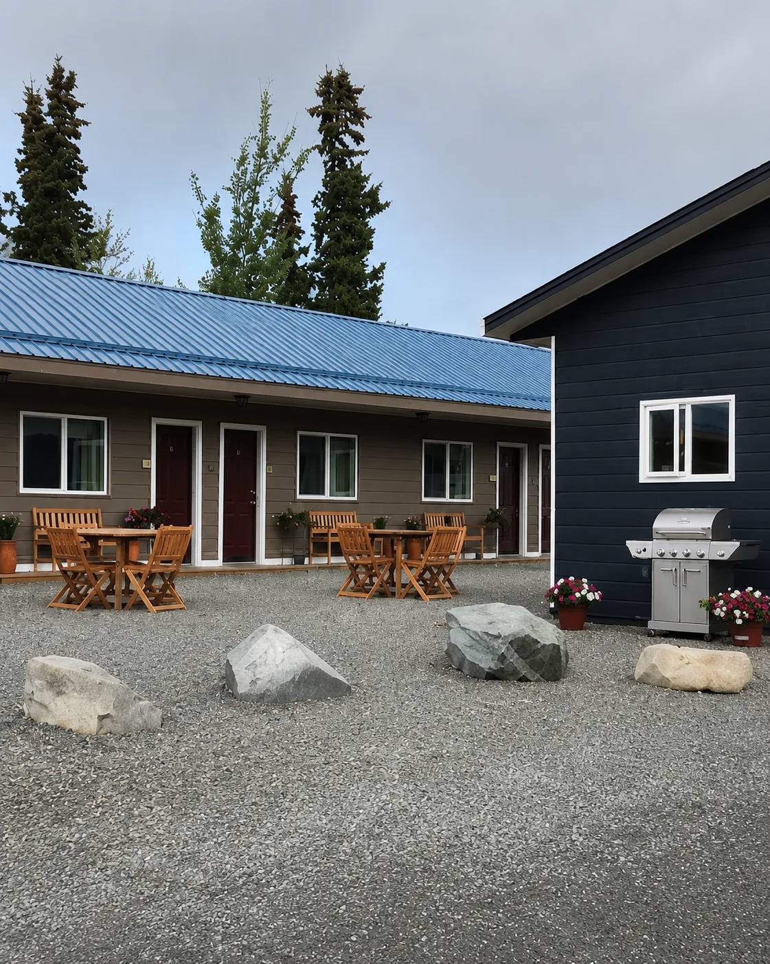 Representative hotel space: A gravel courtyard with outdoor tables, seating, and a grill beside a low building.