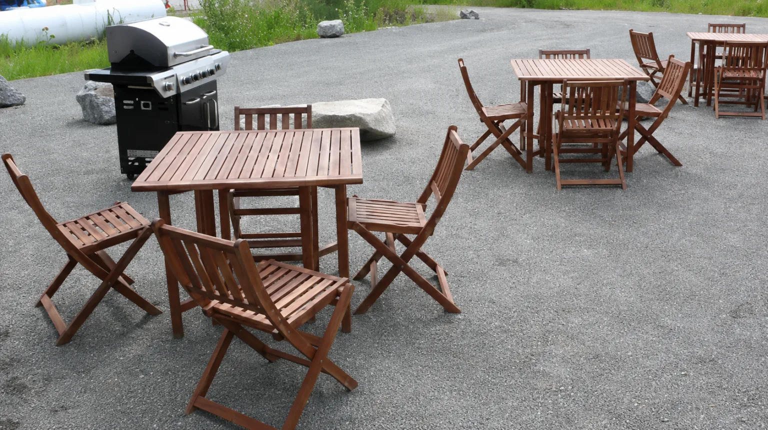 Representative hotel space: An outdoor seating area with wooden tables and folding chairs on a paved surface.