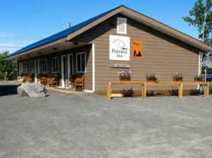 Representative hotel space: A low-rise building with a peaked roof stands beside a paved parking area.