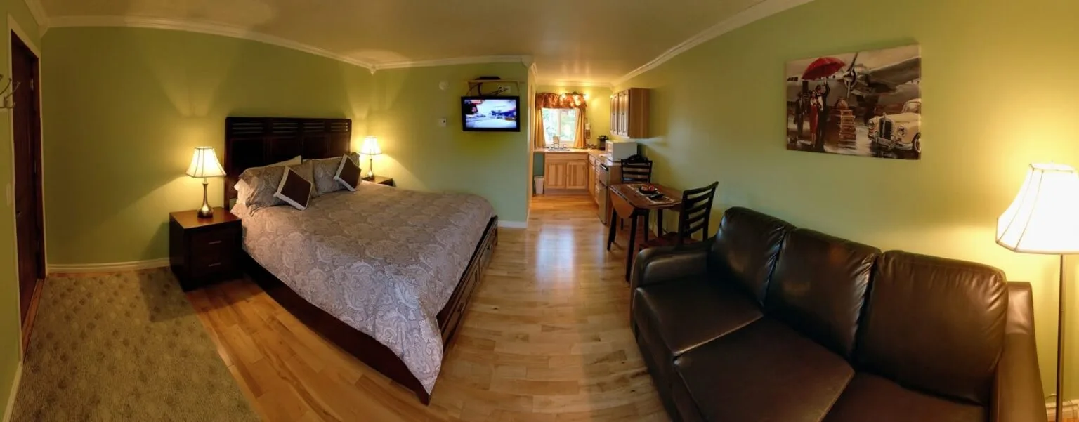 Representative hotel space: A bedroom with a bed, bedside lamps, and a dark couch.