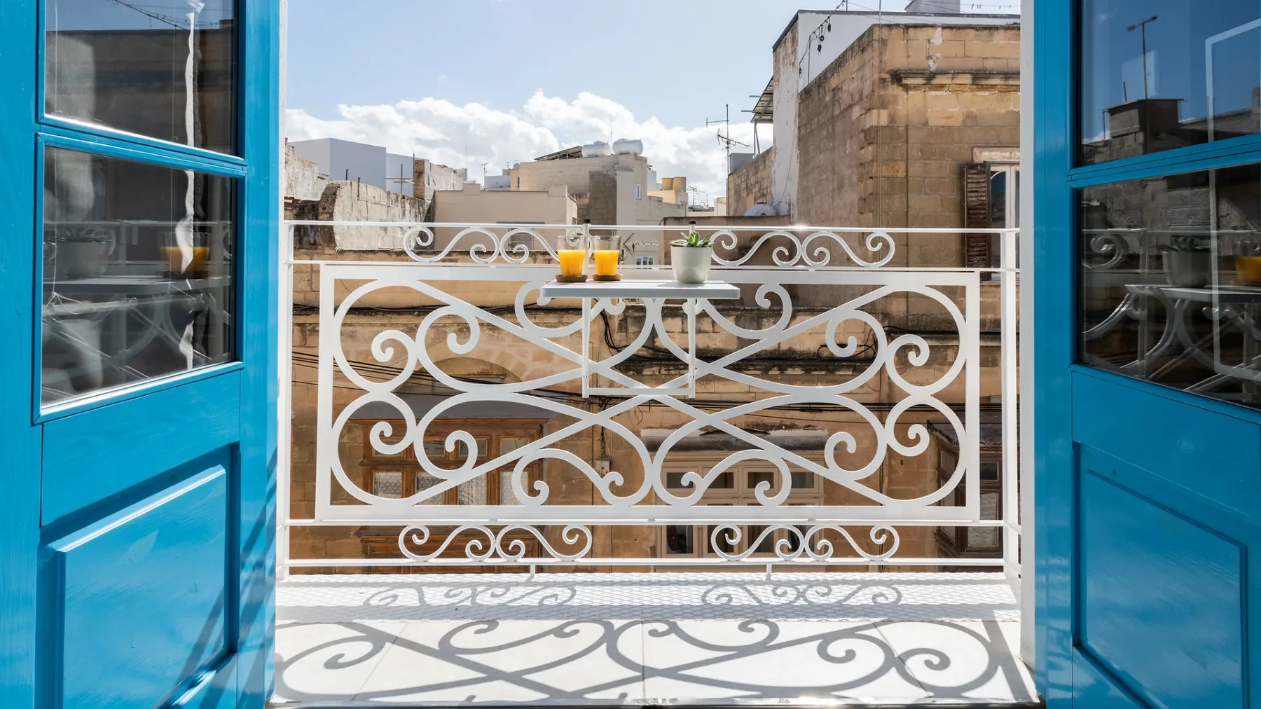 Representative hotel space: A small balcony with ornate white railing and blue doors.
