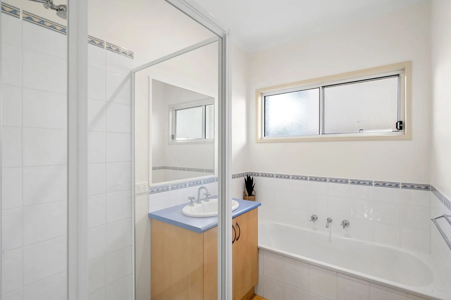 A bright bathroom with a bathtub, tiled walls, and a vanity.