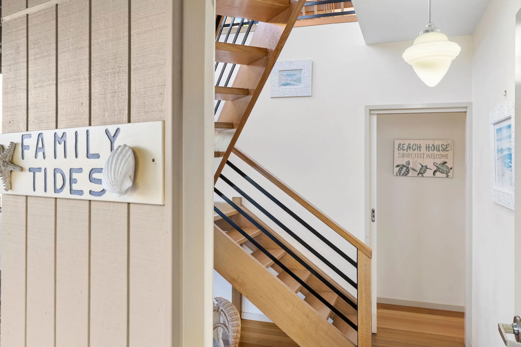 An interior hallway with a wooden staircase and a door.
