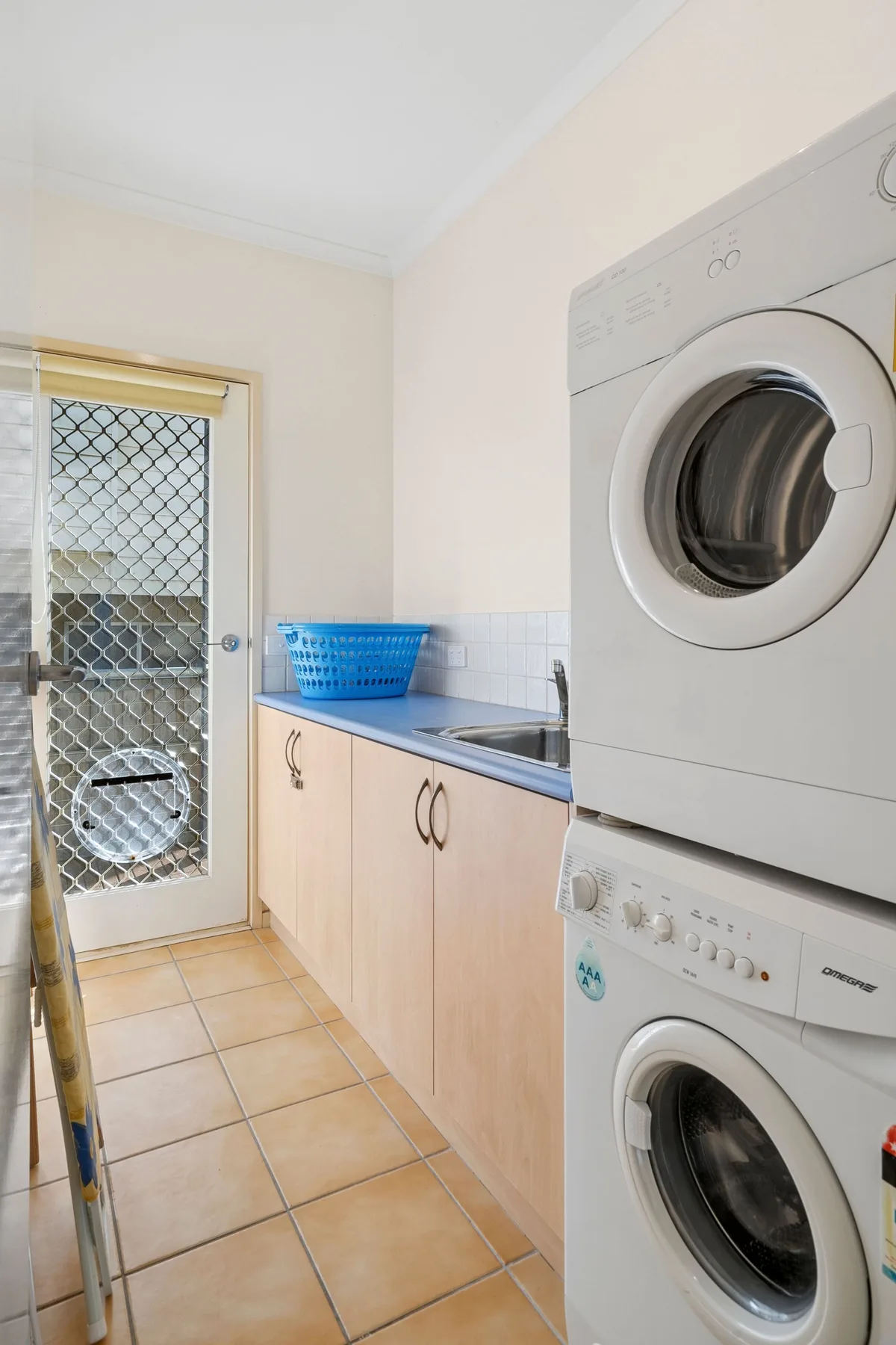A laundry room with stacked washing machines beside a counter and sink.