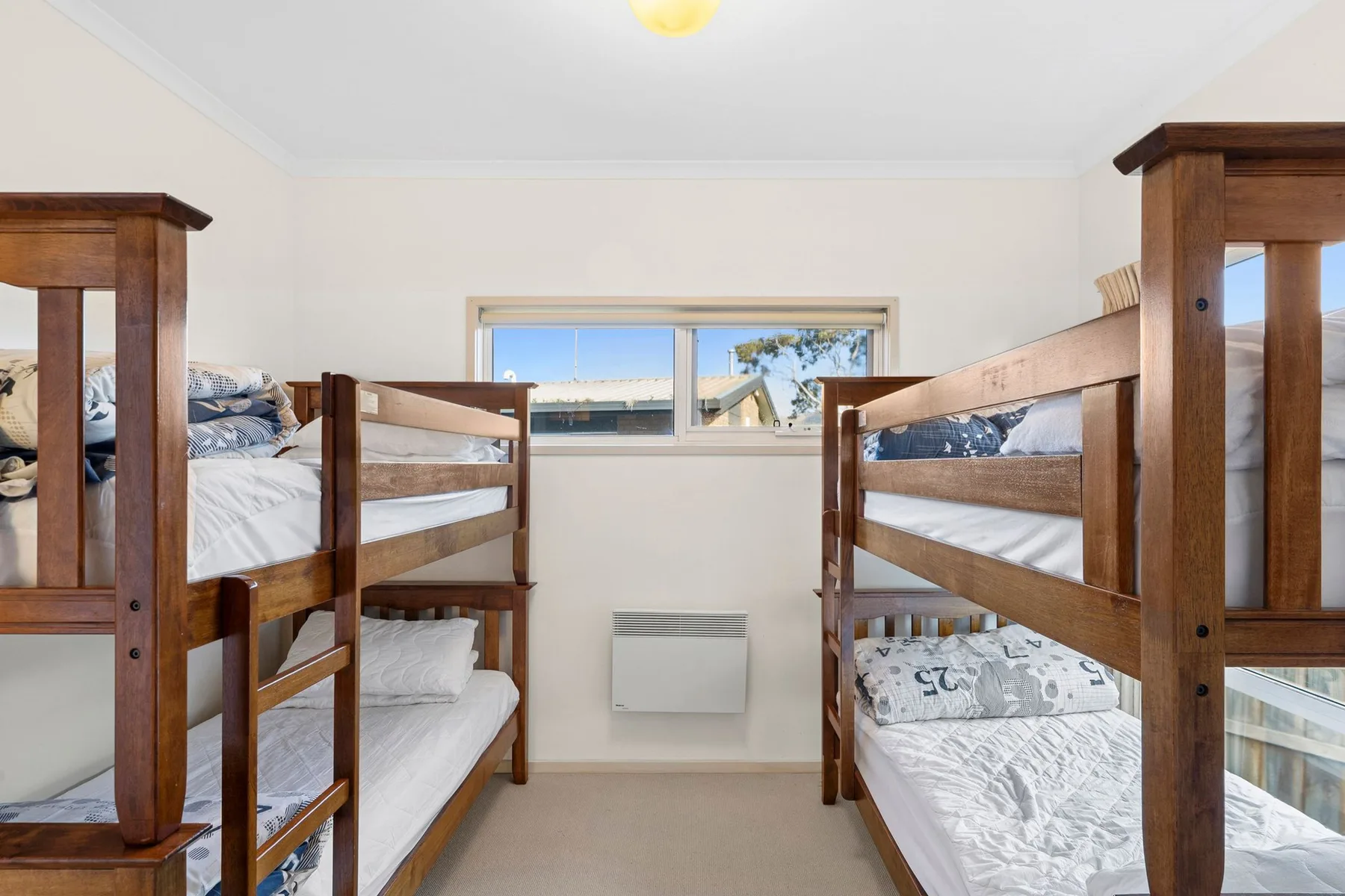 A bedroom with wooden bunk beds and a window.