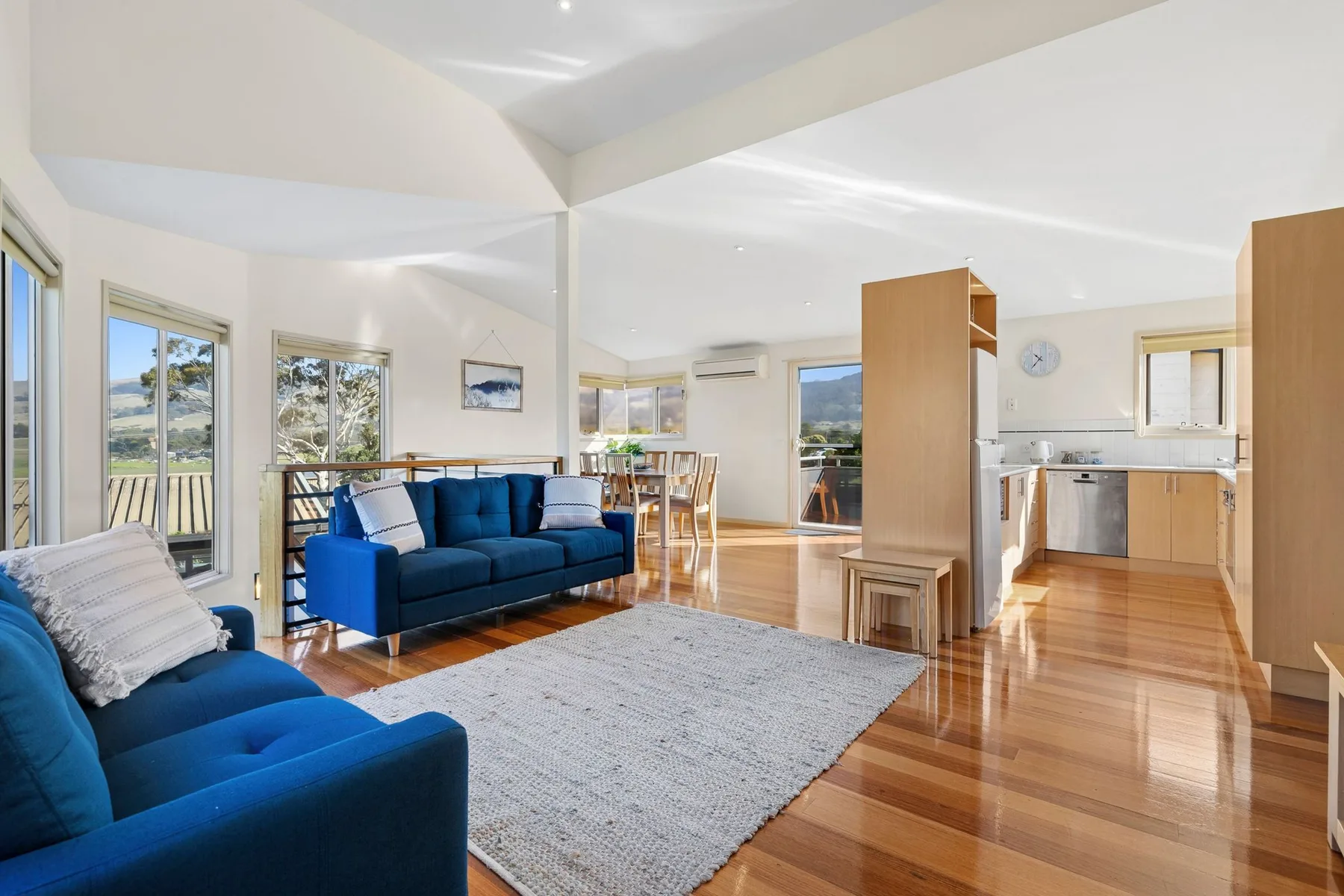 A bright open-plan living area with blue seating and a dining space.