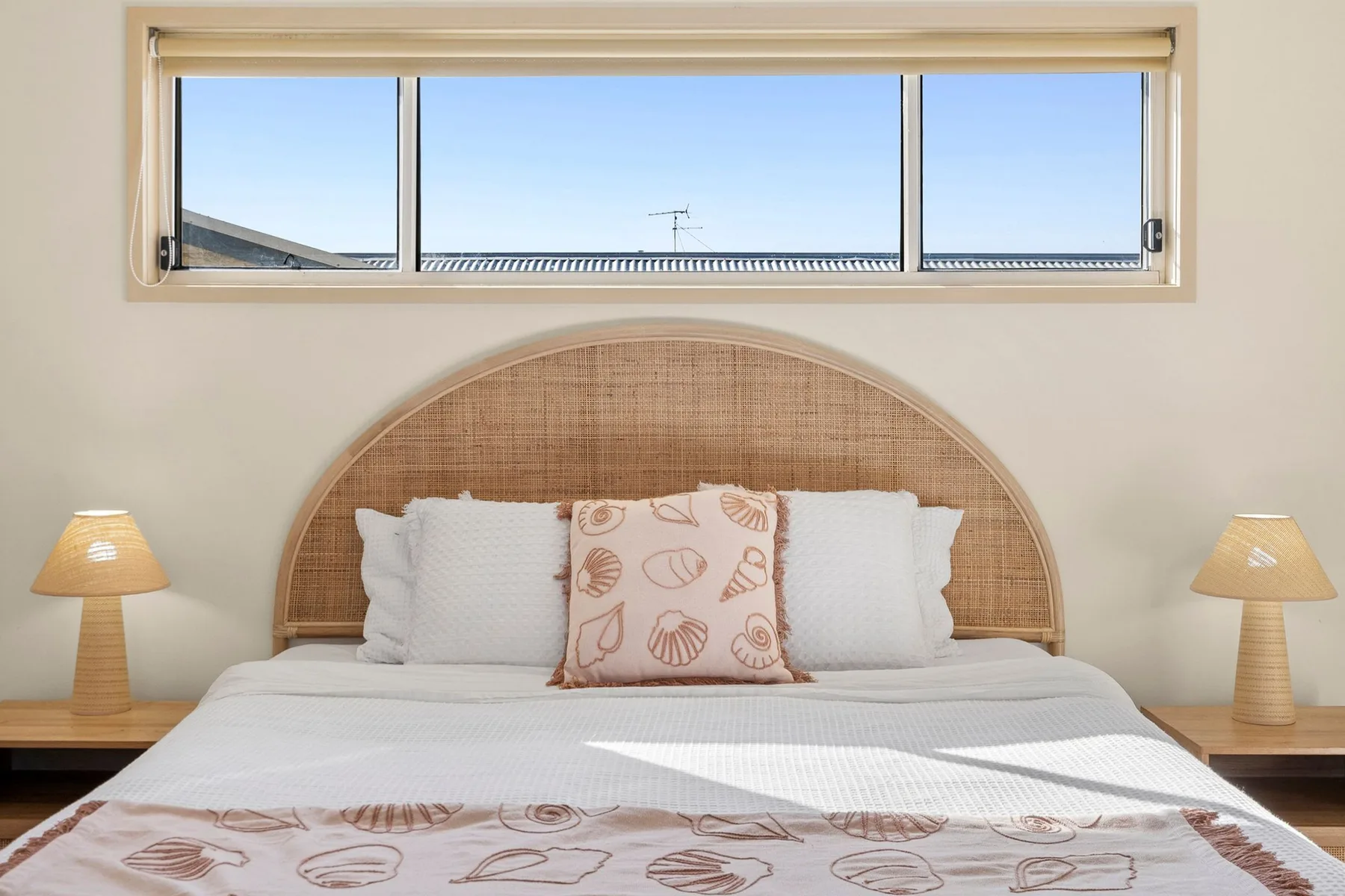 A bedroom with a bed beneath a wide horizontal window.