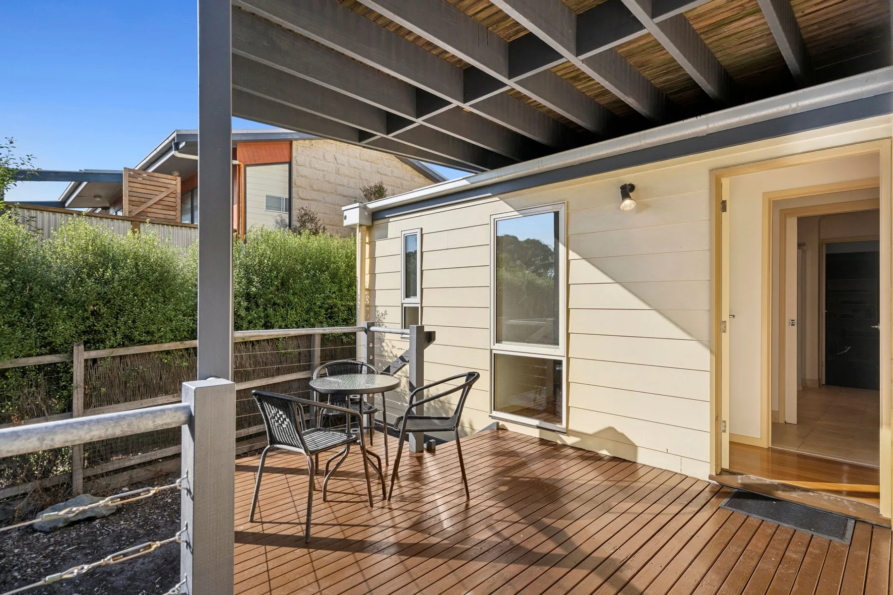 A covered outdoor patio with a small table and seating beside an open doorway.