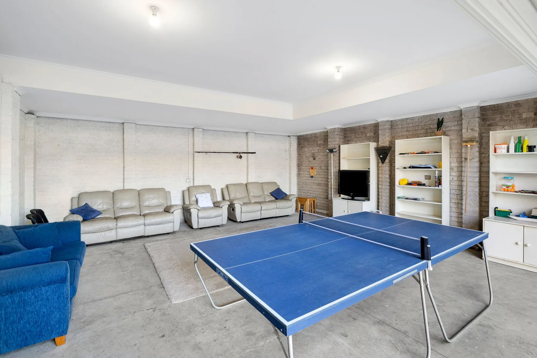 A recreation room with a blue table tennis table and seating.