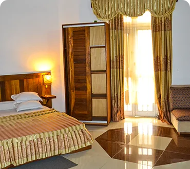 Representative hotel space: A bedroom with a bed beside a curtained window.
