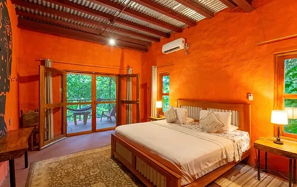 Representative hotel space: A bedroom with a bed beside open glass doors overlooking greenery.