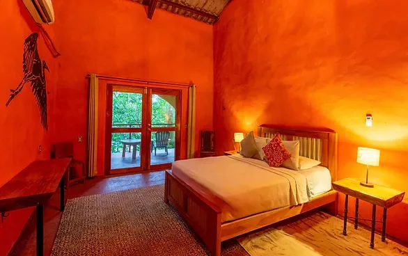 Representative hotel space: A warmly lit bedroom with a wooden bed and glass doors opening to greenery.