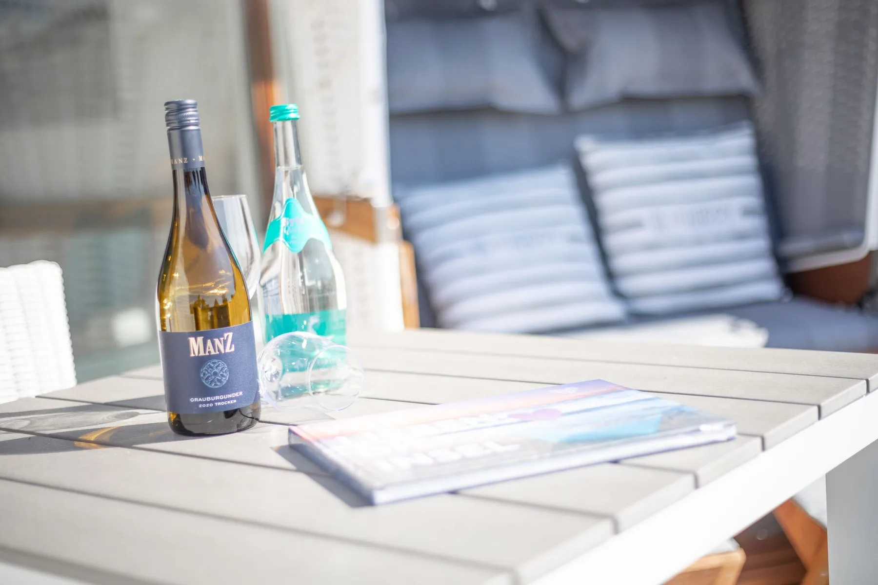 A patio seating area with two bottles and a booklet on a table.