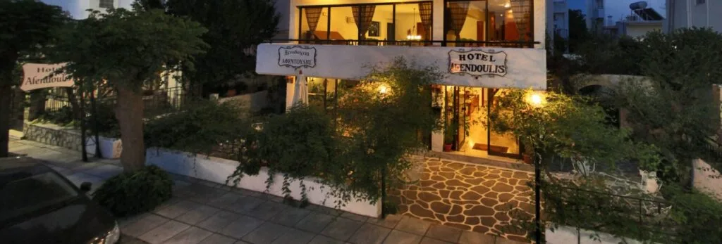 Representative hotel space: A hotel entrance glows at dusk behind a stone walkway and surrounding greenery.