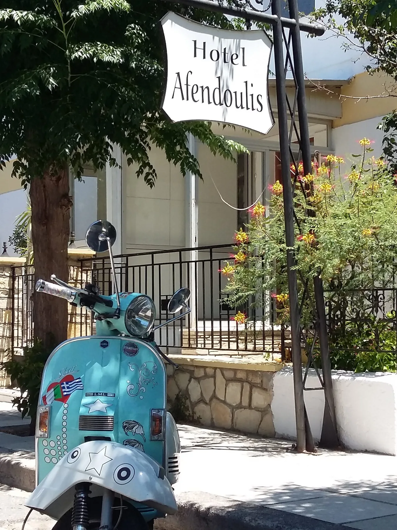 Representative hotel space: A turquoise scooter is parked outside a hotel entrance beneath its sign.