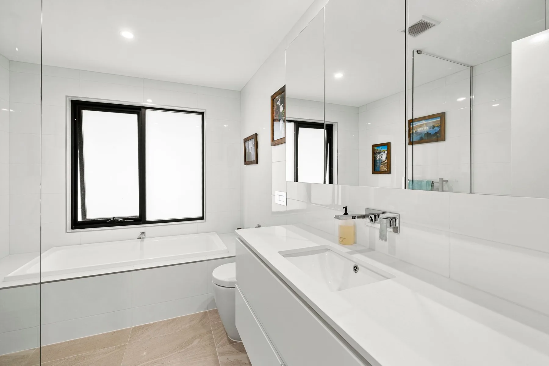 Un baño luminoso con bañera, un espejo grande y un lavabo blanco alargado.