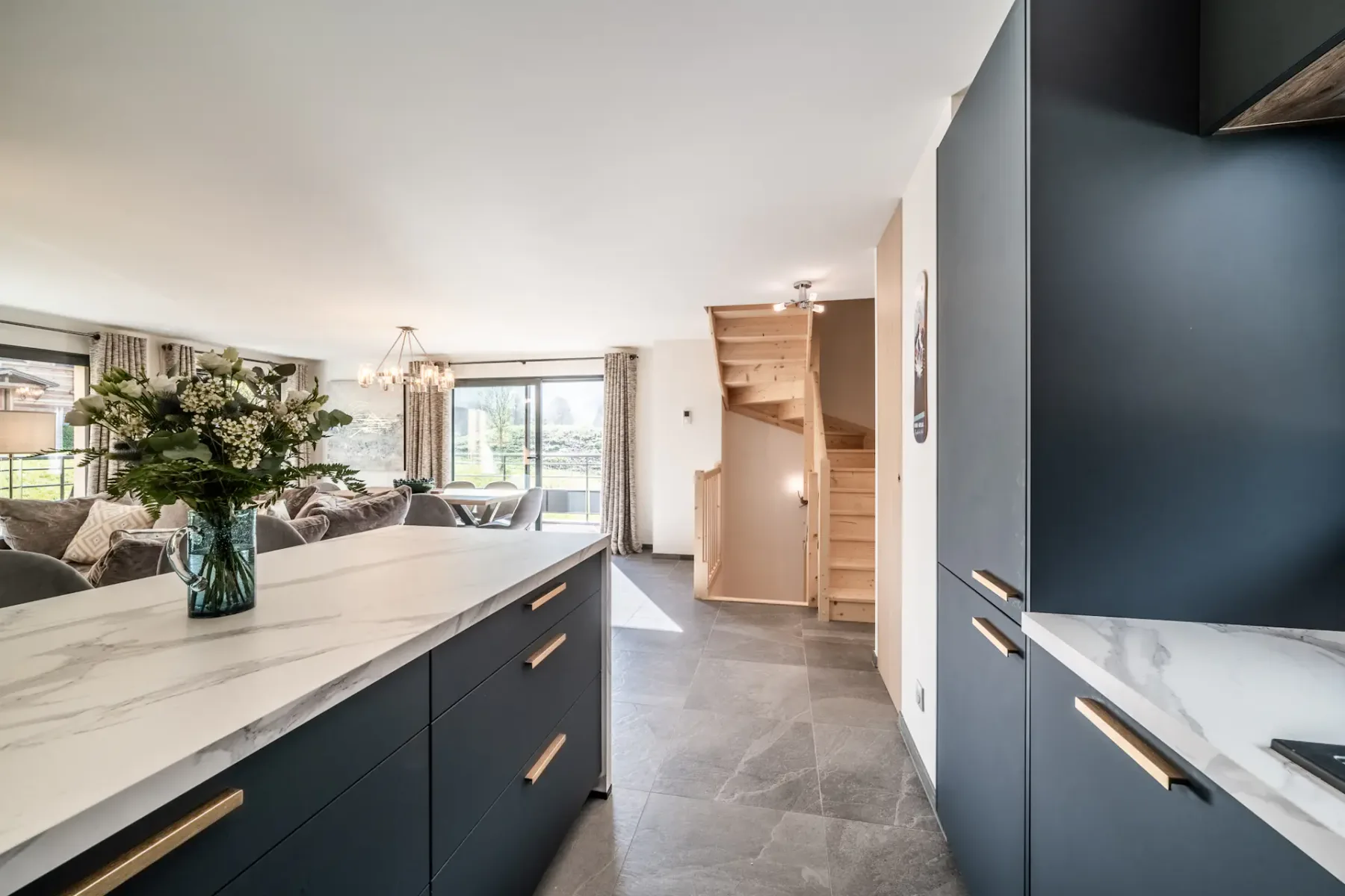 Una cocina moderna se abre a una zona de comedor y sala de estar, con una isla amplia en primer plano.