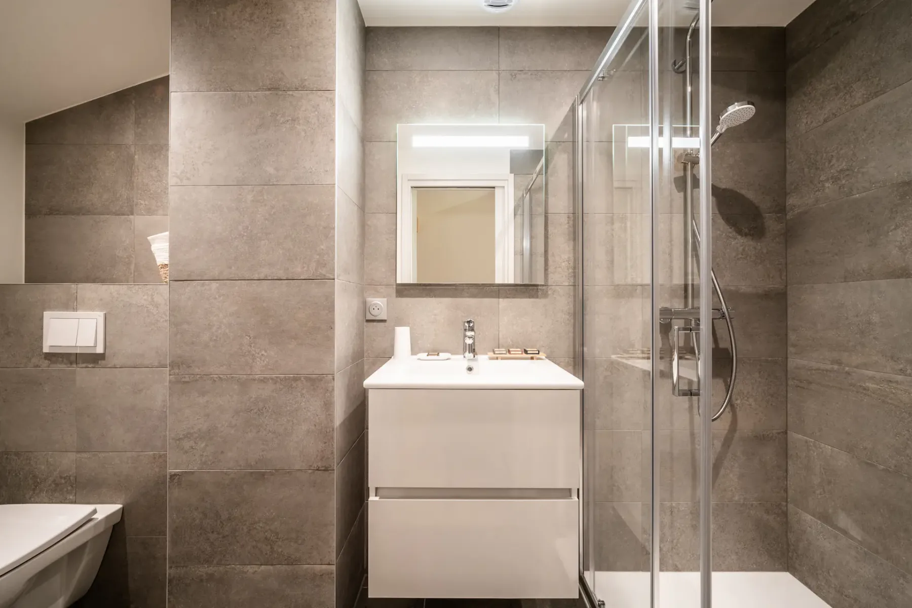 Un baño moderno con un lavabo blanco y una ducha de vidrio.
