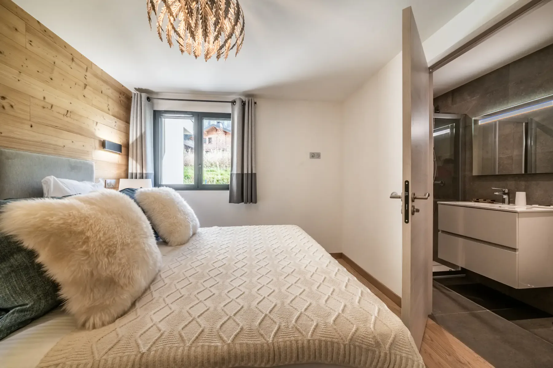 Un dormitorio con una cama junto a una ventana y una puerta abierta al baño.