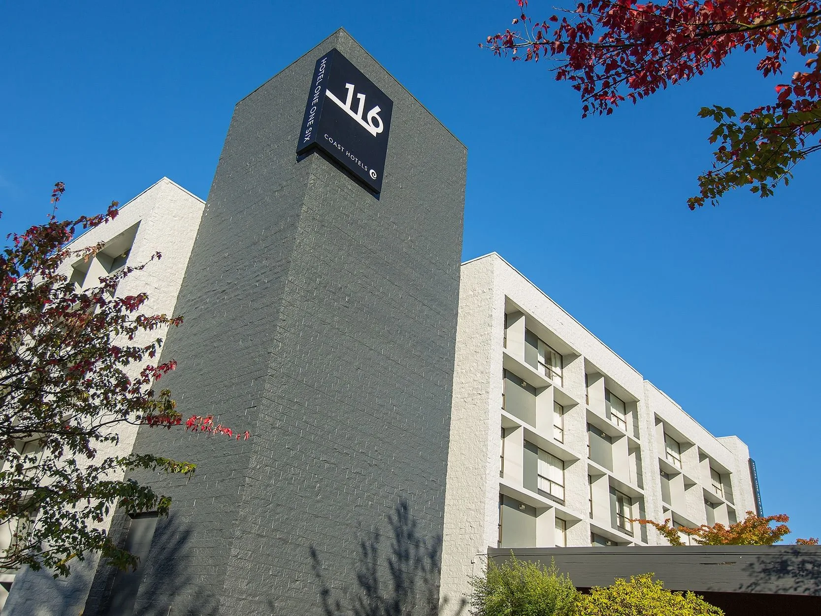 Espacio representativo del hotel: Exterior del hotel con una fachada gris alta y un letrero cerca del techo.