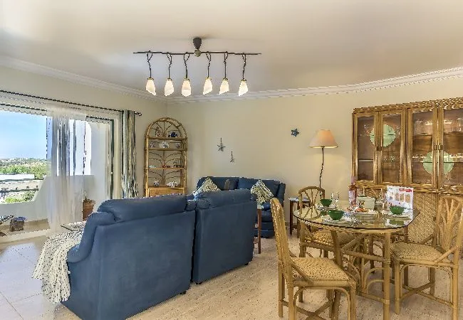 Una sala de estar y comedor con asientos azules y una mesa de comedor de madera.