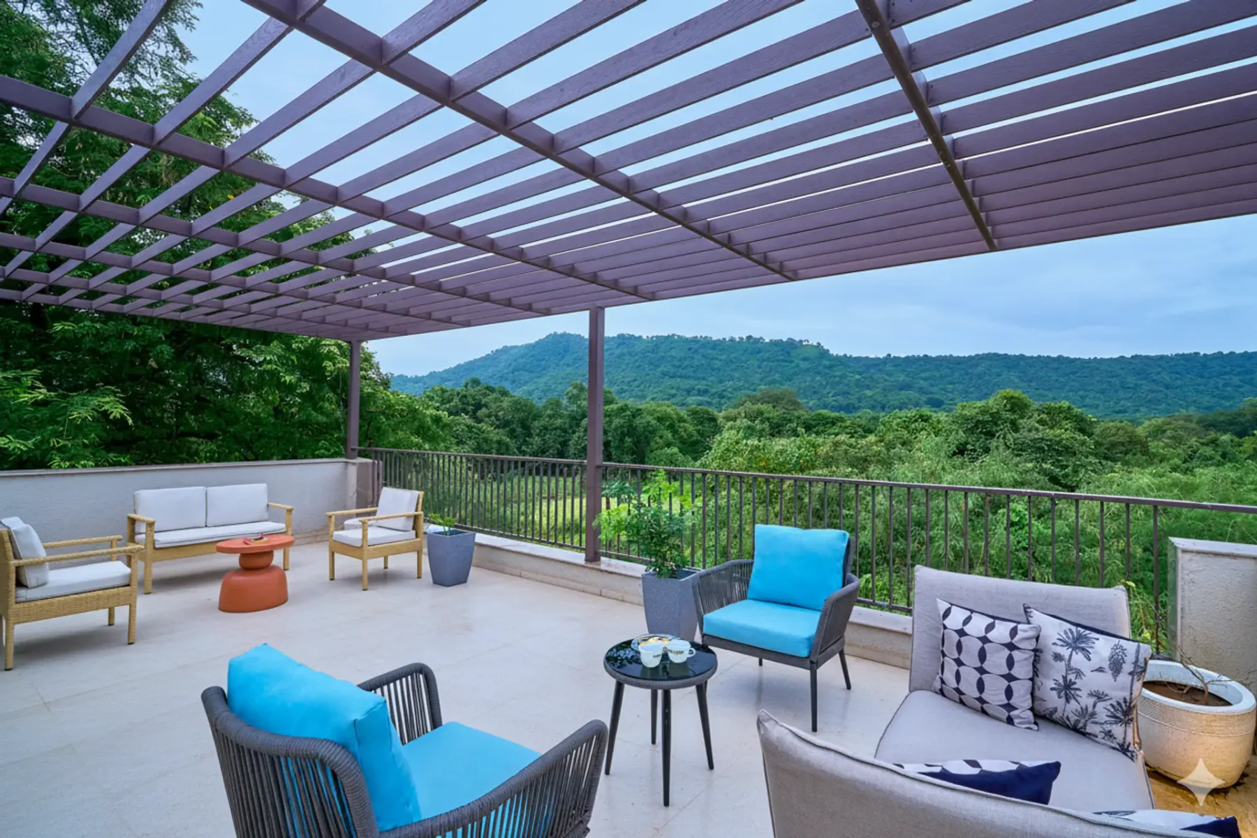 An outdoor terrace with seating beneath a pergola, overlooking green hills.