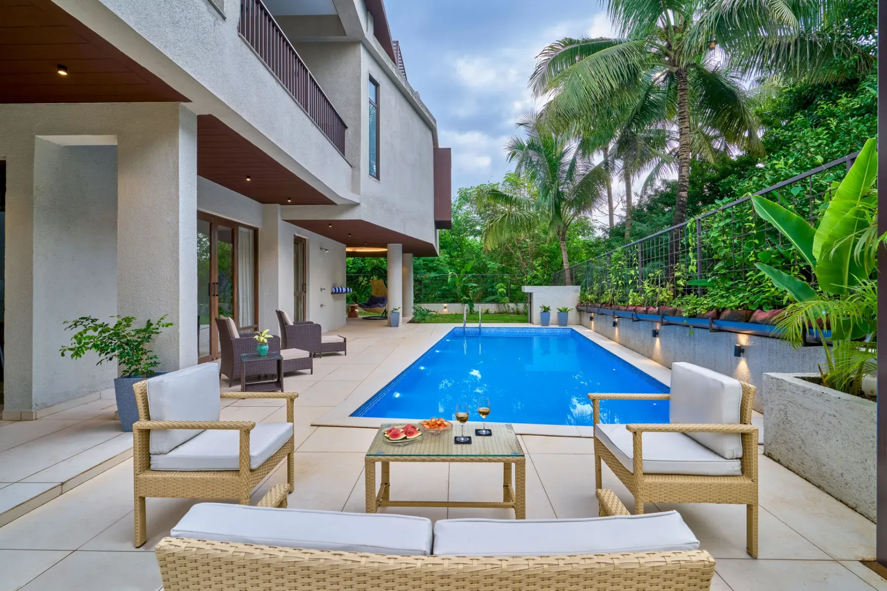 An outdoor swimming pool beside a modern building, with seating on the surrounding patio.