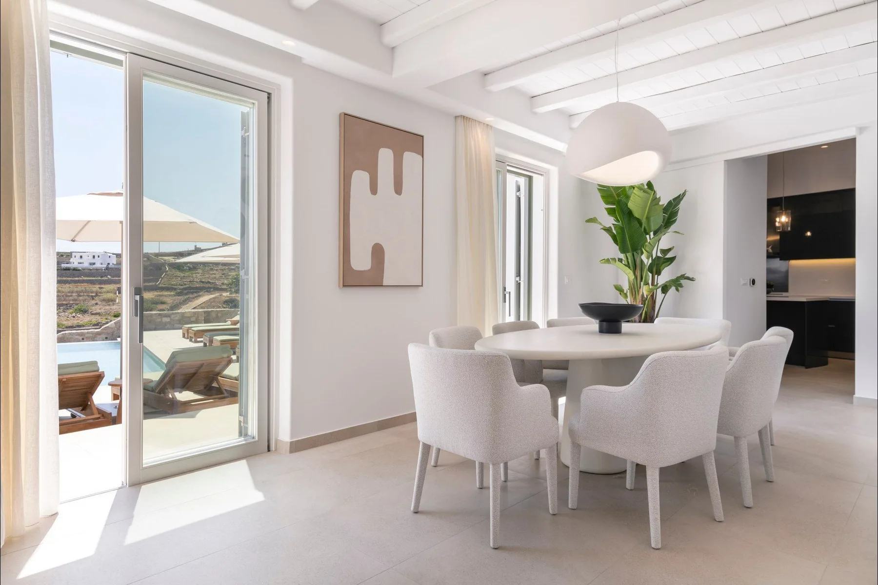 A bright dining area with a round table and large windows overlooking an outdoor patio.