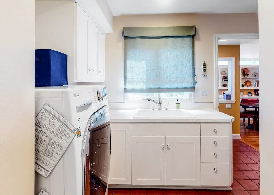 A laundry area with a washer and dryer beside a sink and window.