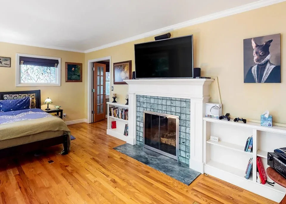 A bedroom with a bed, fireplace, and television.