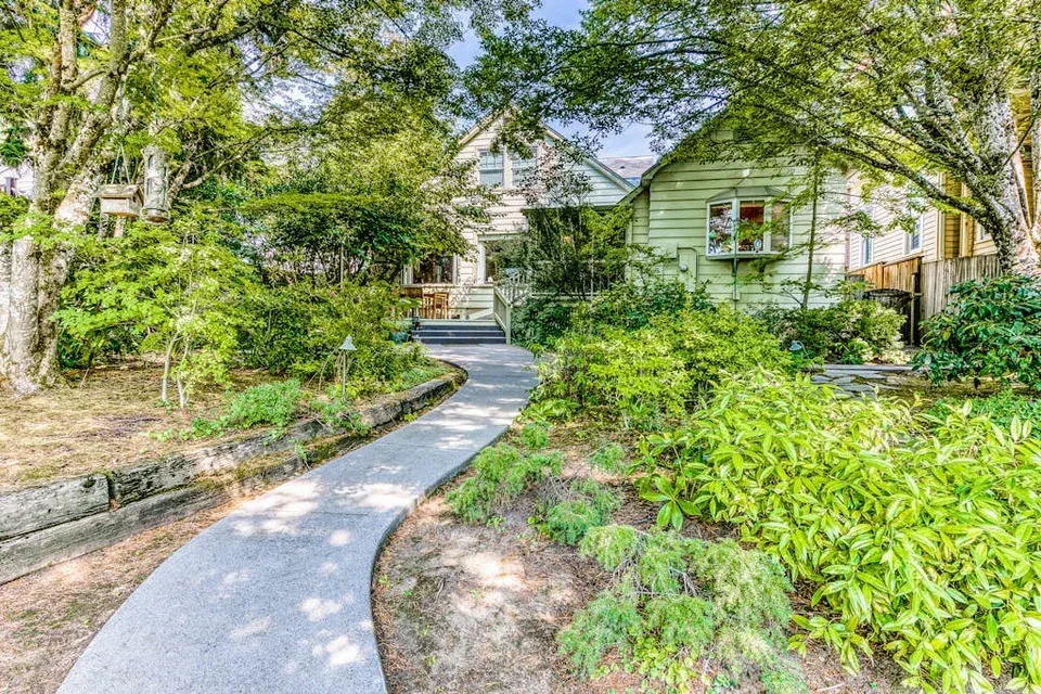 A curved garden path leads through leafy landscaping toward a house.