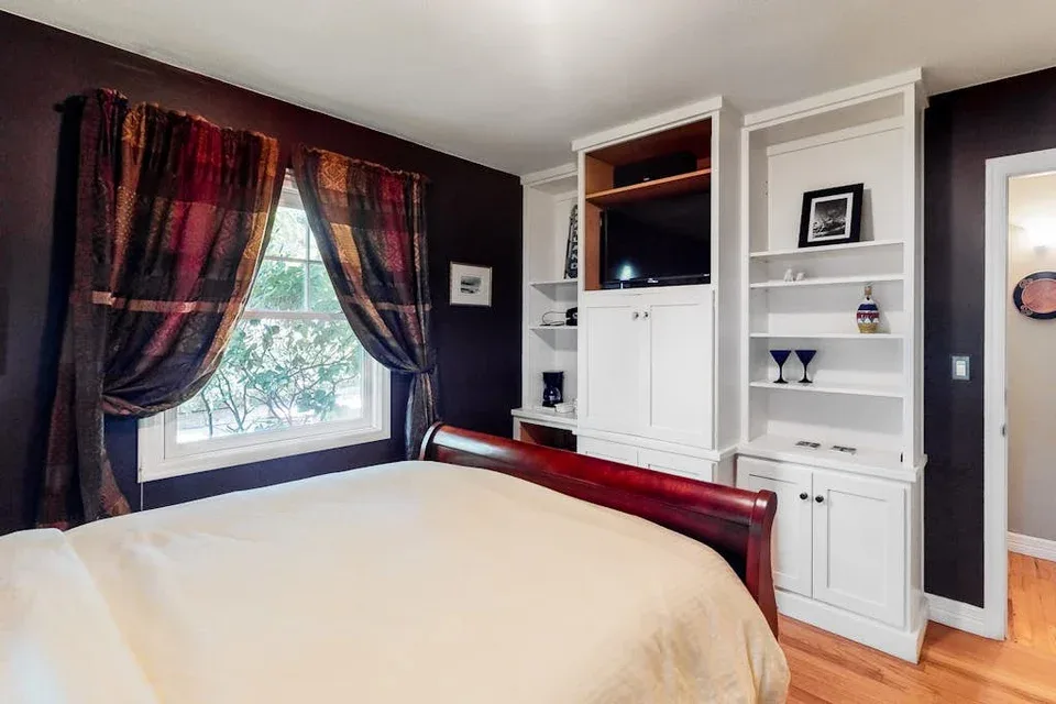 A bedroom with a bed, a window, and built-in white shelving.