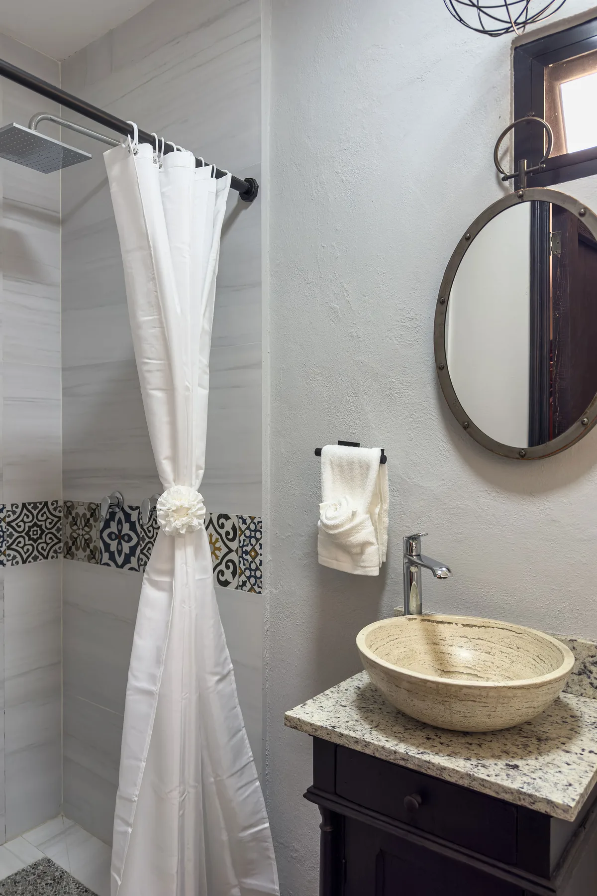 A bathroom with a tied white shower curtain and a vessel sink on a vanity.