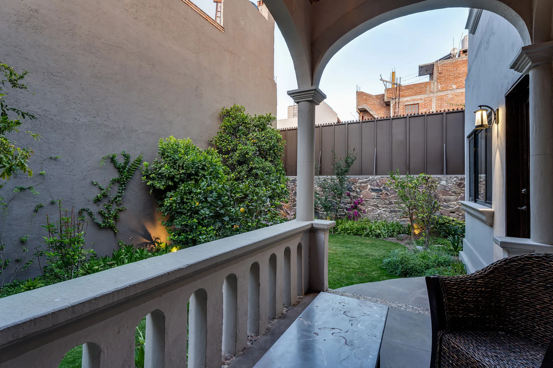 A covered patio overlooks a small garden with shrubs and lawn.