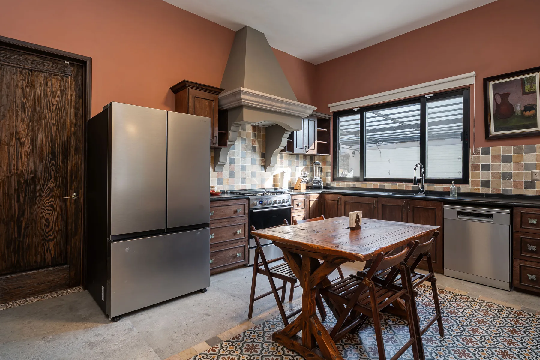 A kitchen with dark wood cabinets, a stainless steel refrigerator, and a dining table.