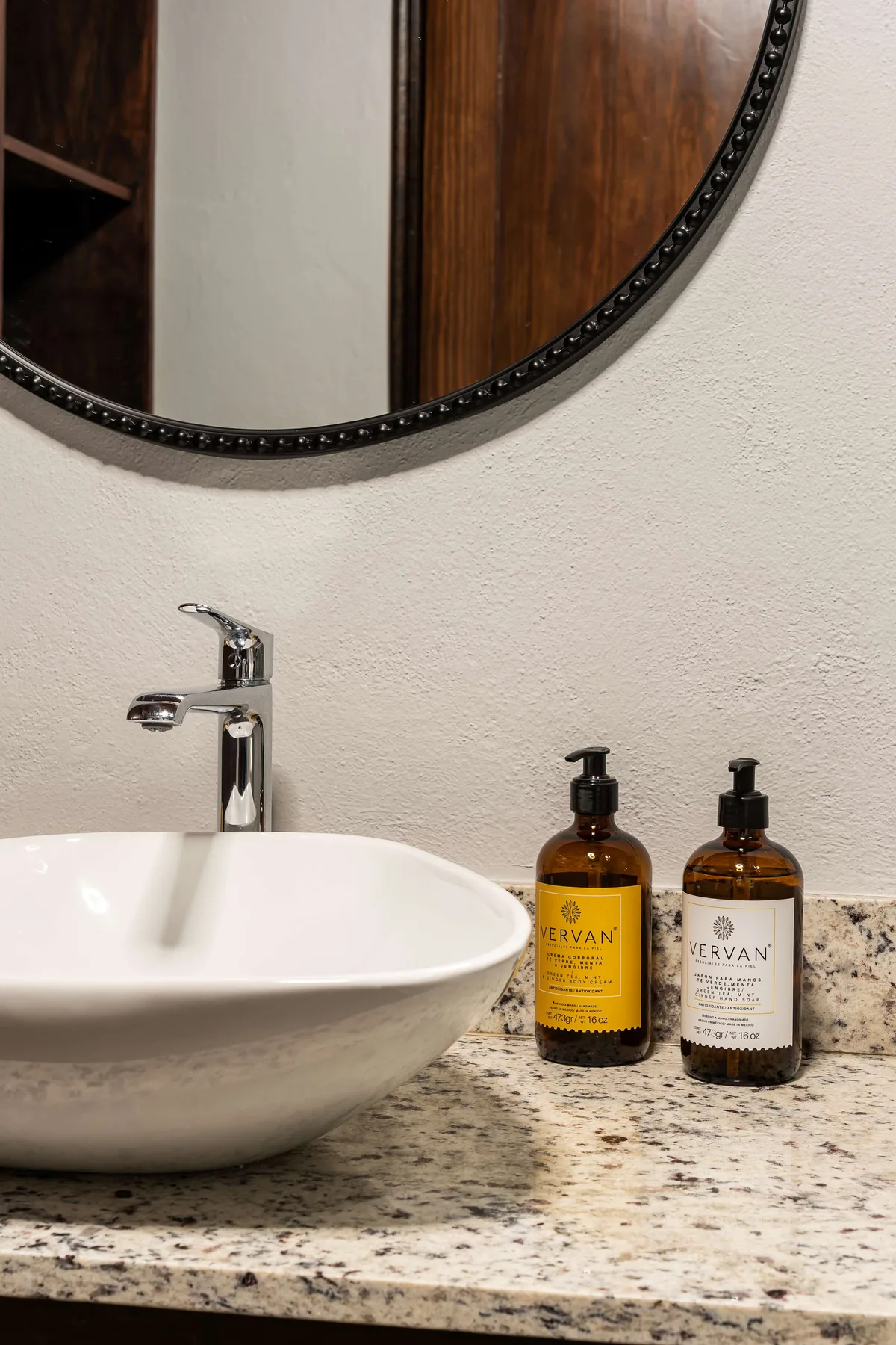 A bathroom vanity with a vessel sink, faucet, and toiletries on the countertop.