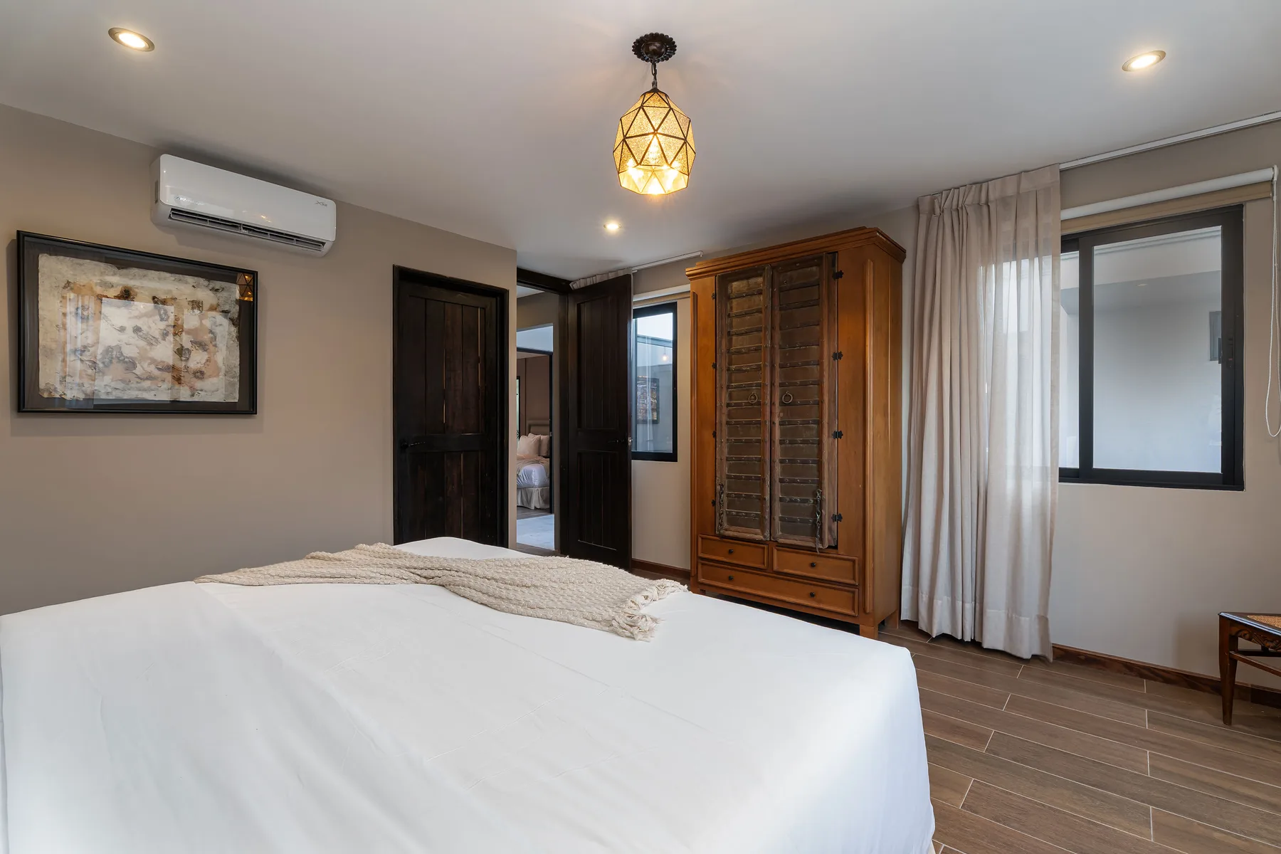 A bedroom with a neatly made bed and a wooden wardrobe.