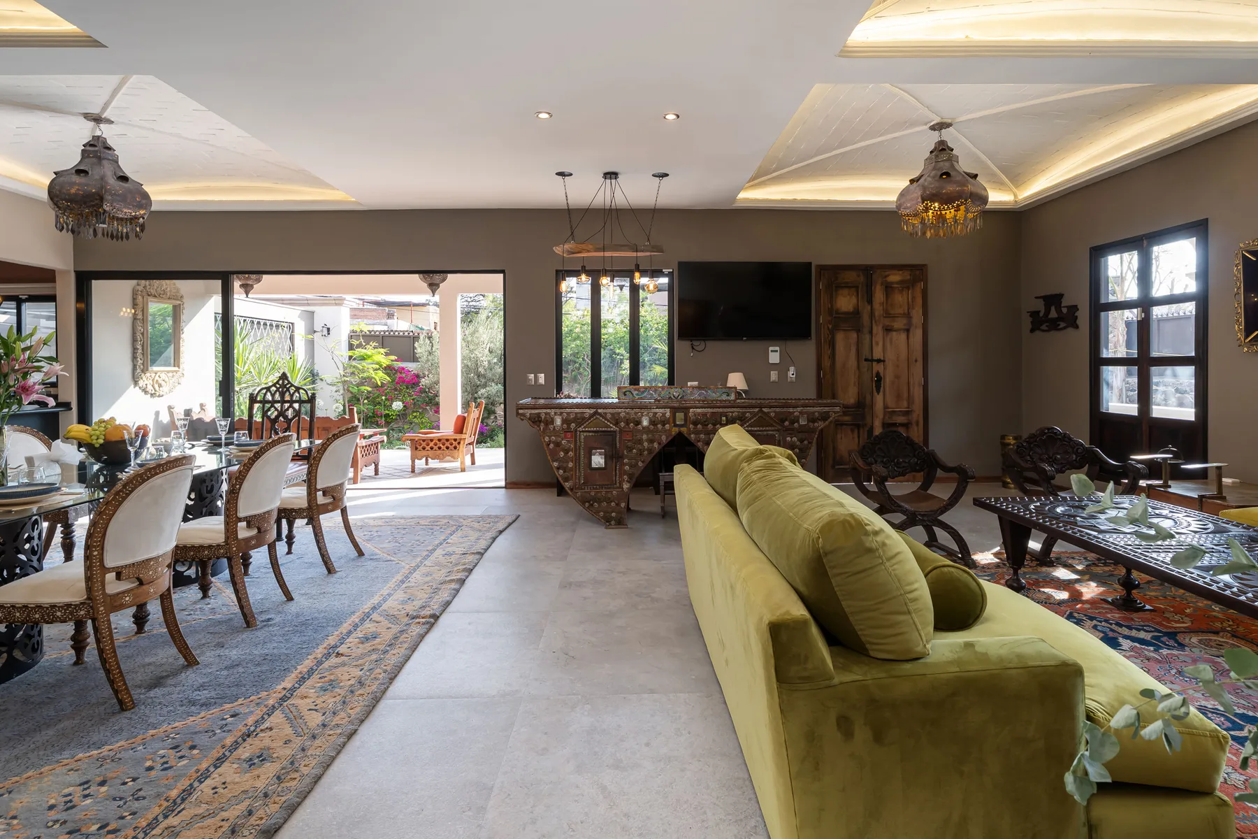 A spacious living and dining room with green seating and an open patio view.