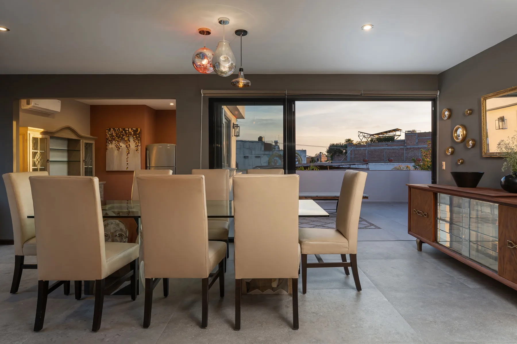 A dining area with upholstered seating, a glass table, and large windows.