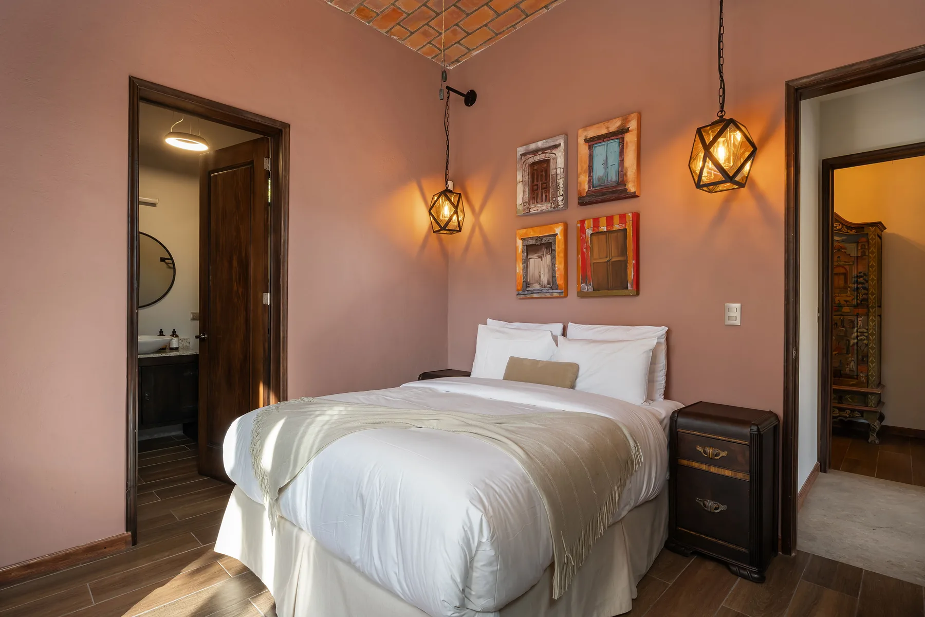 A bedroom with a neatly made bed and framed artwork on the wall.