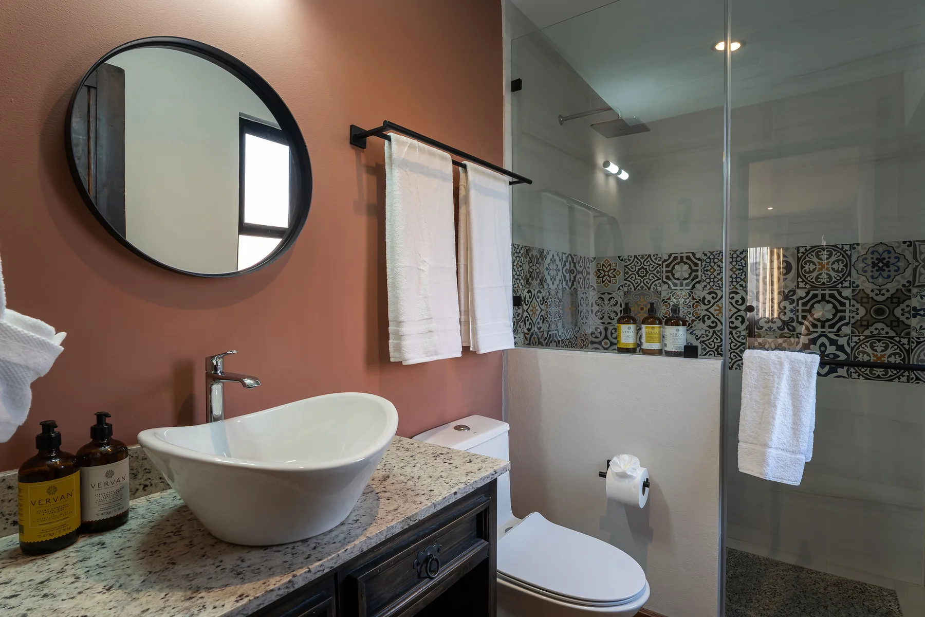 A bathroom with a vessel sink, toilet, and glass shower.