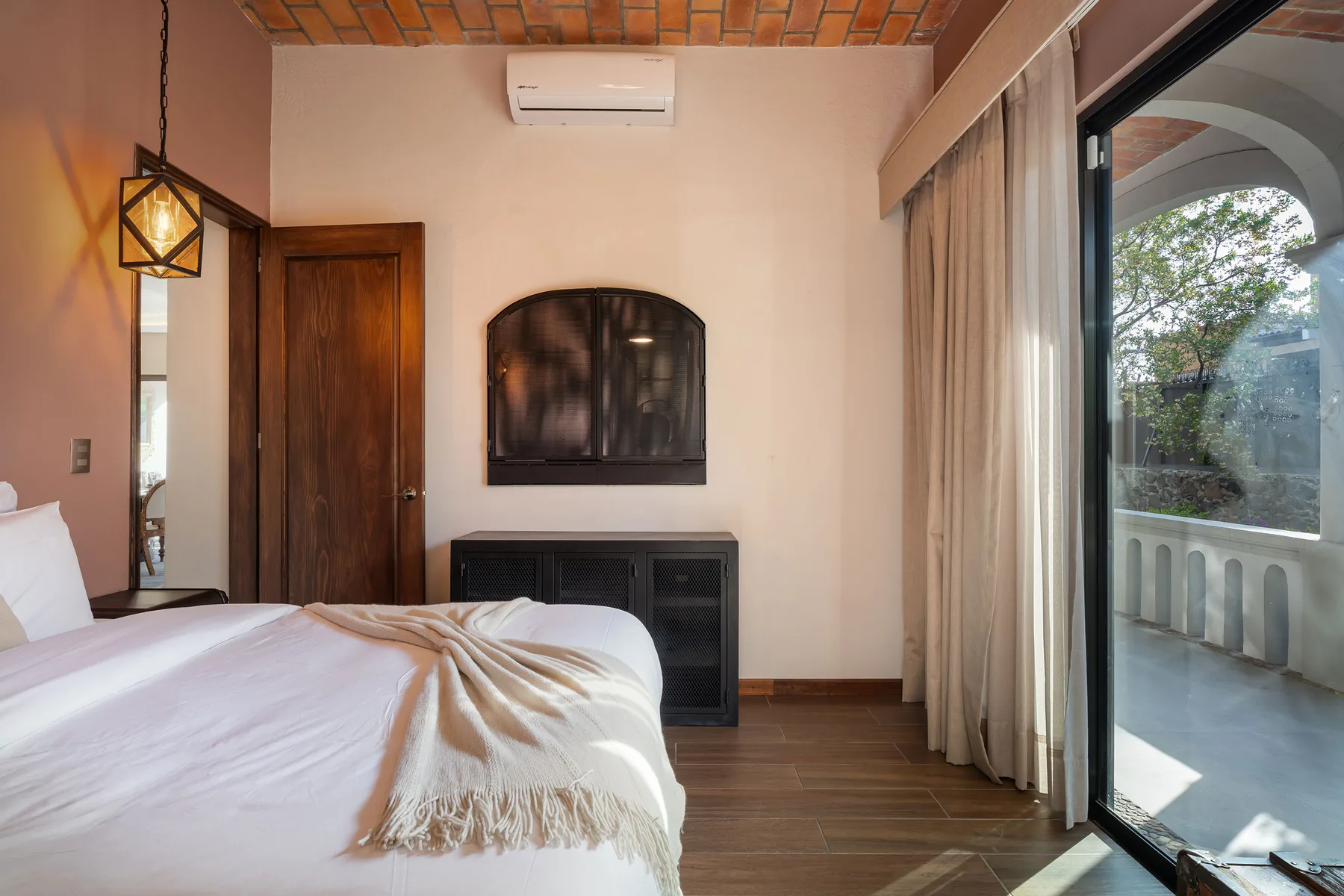 A bedroom with a bed beside a large glass door opening onto a balcony.