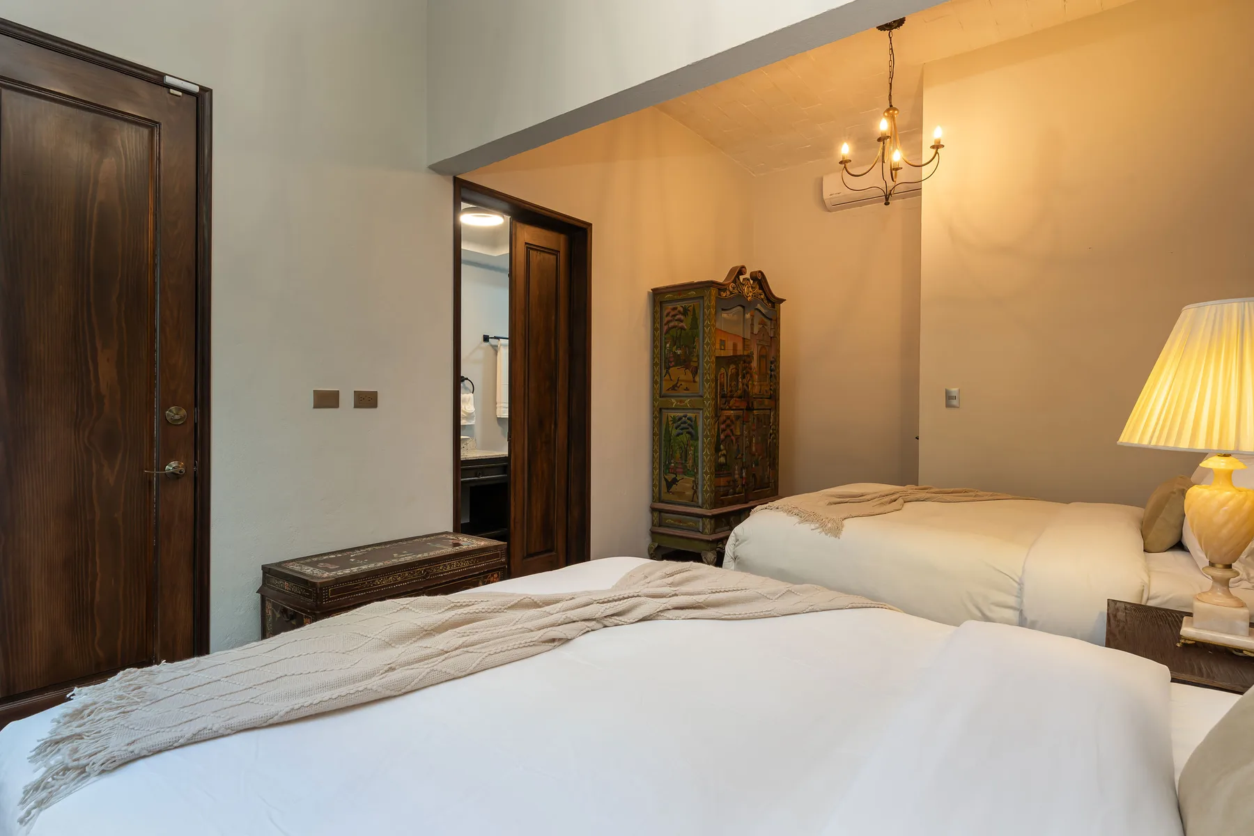 A bedroom with two beds and a carved cabinet between them.
